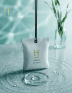 Aqua based perfume in White pouch with gold logo on a textured surface with a blurred background having strong essence with the help of camphor.